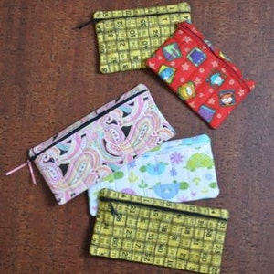 Puede incluir: Cuatro bolsas de tela diferentes con cremalleras. Las bolsas están hechas de diferentes telas con diferentes patrones, incluyendo diseños de paisley, florales y geométricos. Las bolsas están todas cerradas y tienen cremalleras negras.