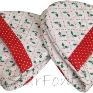 May include: Two white fabric pot holders with a red and white polka dot trim and a green holly leaf pattern. The pot holders are quilted and have a red and white polka dot trim.