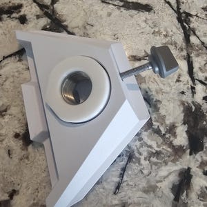 May include: White plastic triangular mounting bracket with a threaded hole and a grey knob.