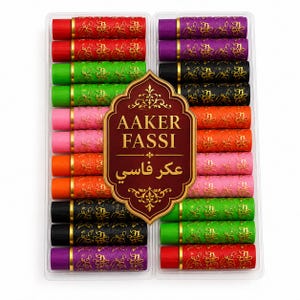 Könnte beinhalten: Ein Set von Aaker Fassi Kosmetikstiften in einer transparenten Kunststoffschale. Die zylindrischen Stifte haben eine strukturierte Oberfläche mit einem goldenen Blumenmuster und sind in Rot, Grün, Pink, Orange, Schwarz und Lila erhältlich.