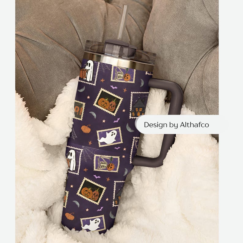 May include: A dark purple stainless steel tumbler with a handle, a clear lid, and a straw. The exterior features a repeating pattern of postage stamp-style illustrations depicting ghosts, pumpkins, and haunted houses. The text Design by Althafco is visible.