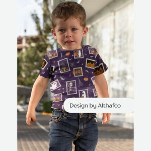 May include: A short-sleeved t-shirt in a deep purple hue featuring a repeating pattern of rectangular postage stamp-style graphics with Halloween motifs including ghosts, skeletons, pumpkins, and haunted houses. The text Design by Althafco is visible.