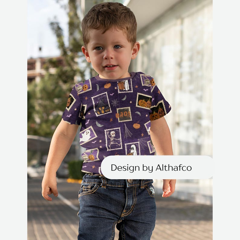 May include: A short-sleeved t-shirt in a deep purple hue featuring a repeating pattern of rectangular postage stamp-style graphics with Halloween motifs including ghosts, skeletons, pumpkins, and haunted houses. The text Design by Althafco is visible.