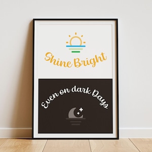 May include: A framed print with a black and white background. The top half is white with a yellow sun and the text "Shine Bright". The bottom half is black with a gray moon and the text "Even on dark days".