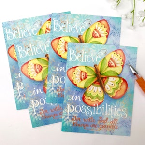 May include: Four blue and yellow cards with a butterfly design and the text "Believe in possibilities. For with God all things are possible." The butterfly is yellow with red, green, and white accents. The background is a light blue with white flowers.