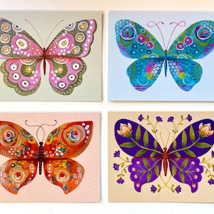May include: Four colorful butterfly art prints. Each butterfly has a unique design with vibrant colors. One butterfly is pink and green, another is blue and teal, the third is orange and red, and the last is purple with floral accents.