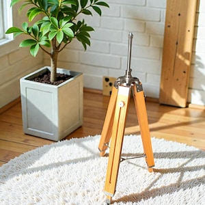 Vintage-style adjustable tripod stand handcrafted from premium teak wood with polished aluminium and nickel hardware. Features three sturdy wooden legs, an adjustable center column, and a height range of 25 to 50 inches. Ideal for DIY photo booths, DSLR cameras, floor lamps, studio décor, and nautical-inspired interiors. Handcrafted wooden tripod with a timeless industrial design.