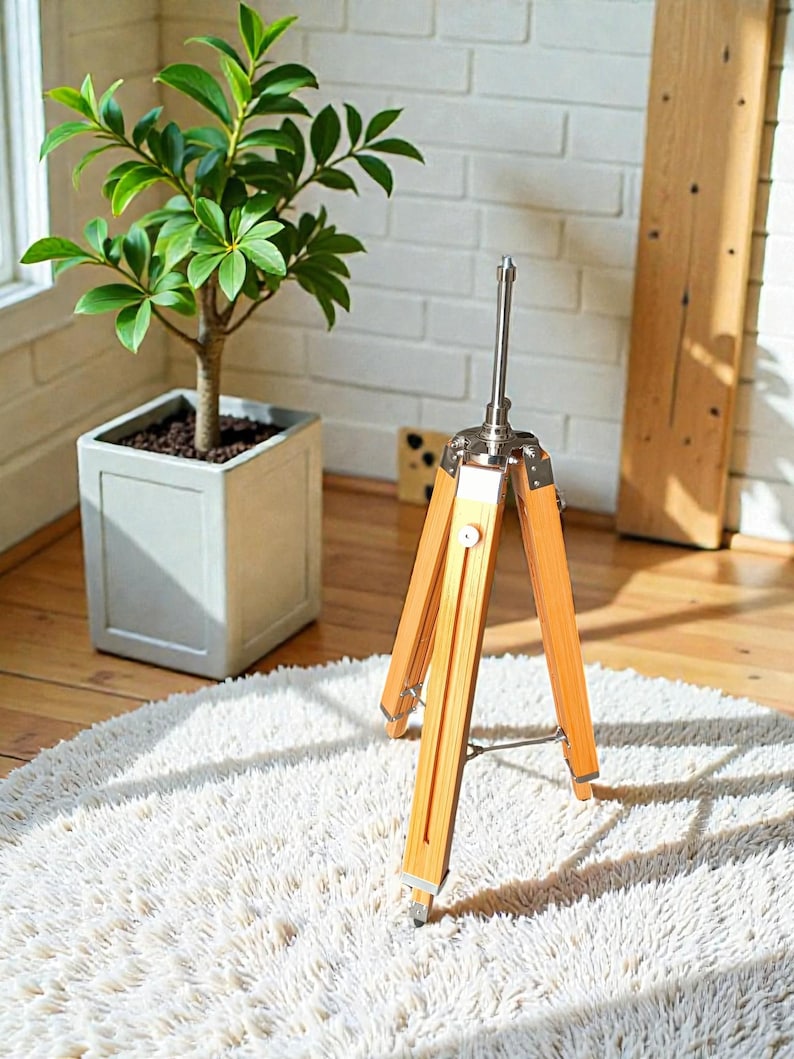 Vintage-style adjustable tripod stand handcrafted from premium teak wood with polished aluminium and nickel hardware. Features three sturdy wooden legs, an adjustable center column, and a height range of 25 to 50 inches. Ideal for DIY photo booths, DSLR cameras, floor lamps, studio décor, and nautical-inspired interiors. Handcrafted wooden tripod with a timeless industrial design.
