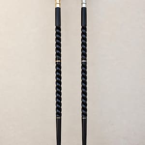 May include: Two walking sticks with black, spiraled shafts. One features a polished gold-tone handle and tip, while the other has a polished silver-tone handle and tip. Both sticks have a smooth, tapered lower section and a rounded, knob-style top.