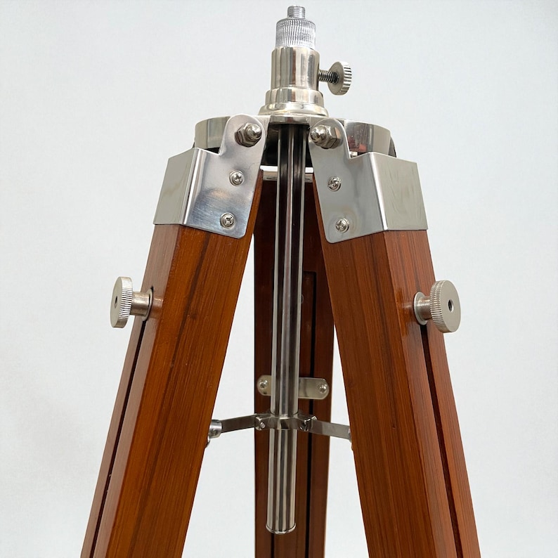 Vintage-style adjustable tripod stand handcrafted from premium teak wood with polished aluminium and nickel hardware. Features three sturdy wooden legs, an adjustable center column, and a height range of 25 to 50 inches. Ideal for DIY photo booths, DSLR cameras, floor lamps, studio décor, and nautical-inspired interiors. Handcrafted wooden tripod with a timeless industrial design.