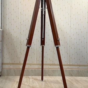 For a camera tripod: "Wooden three-legged camera tripod with adjustable legs and a ball head mount"
For a display/easel: "A natural wood tripod easel stand with splayed legs for stability"
For a plant/decorative stand: "Rustic wooden tripod plant stand with angled legs joined at the top"