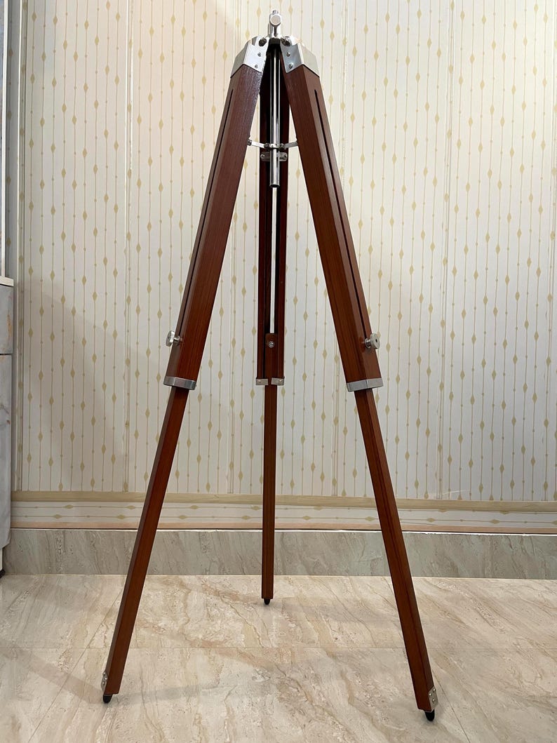 For a camera tripod: "Wooden three-legged camera tripod with adjustable legs and a ball head mount"
For a display/easel: "A natural wood tripod easel stand with splayed legs for stability"
For a plant/decorative stand: "Rustic wooden tripod plant stand with angled legs joined at the top"