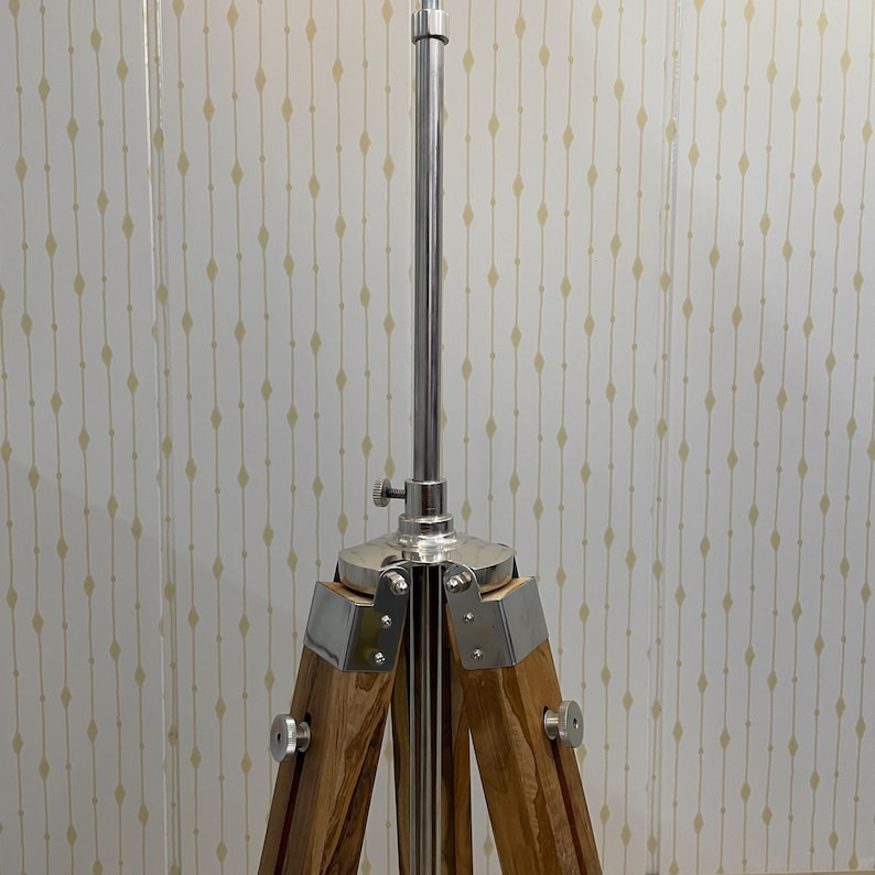 Vintage-style adjustable tripod stand handcrafted from premium teak wood with polished aluminium and nickel hardware. Features three sturdy wooden legs, an adjustable center column, and a height range of 25 to 50 inches. Ideal for DIY photo booths, DSLR cameras, floor lamps, studio décor, and nautical-inspired interiors. Handcrafted wooden tripod with a timeless industrial design.