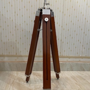 Vintage-style adjustable tripod stand handcrafted from premium teak wood with polished aluminium and nickel hardware. Features three sturdy wooden legs, an adjustable center column, and a height range of 25 to 50 inches. Ideal for DIY photo booths, DSLR cameras, floor lamps, studio décor, and nautical-inspired interiors. Handcrafted wooden tripod with a timeless industrial design.