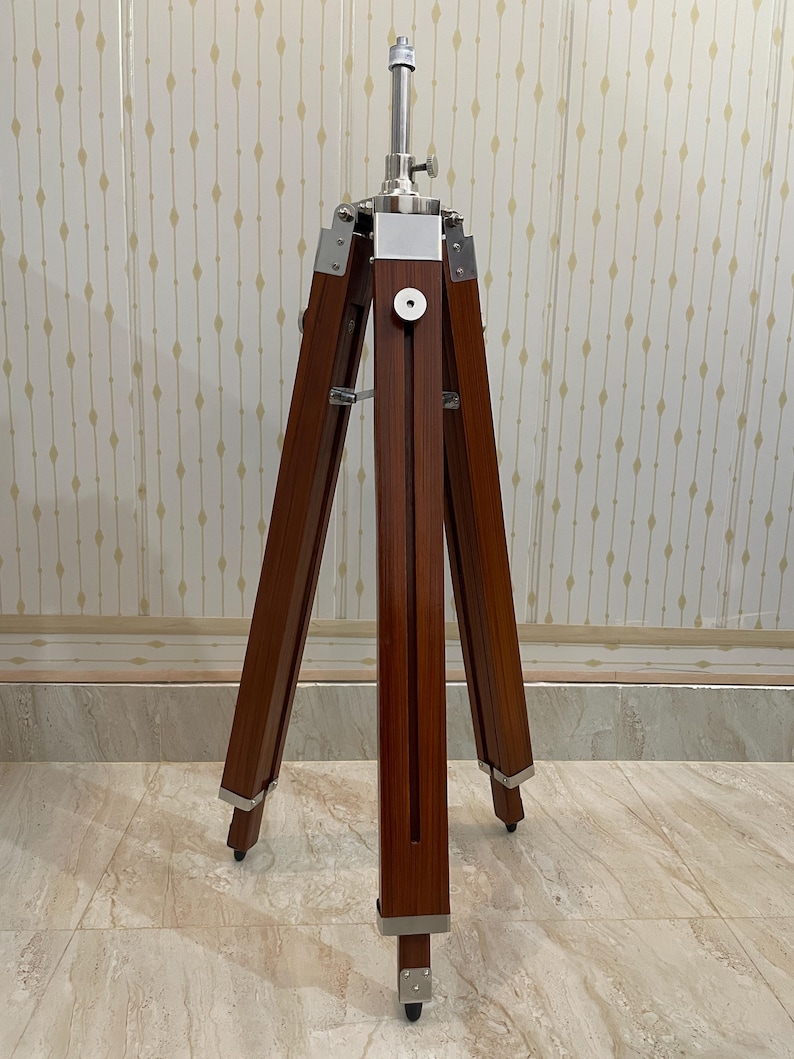 Vintage-style adjustable tripod stand handcrafted from premium teak wood with polished aluminium and nickel hardware. Features three sturdy wooden legs, an adjustable center column, and a height range of 25 to 50 inches. Ideal for DIY photo booths, DSLR cameras, floor lamps, studio décor, and nautical-inspired interiors. Handcrafted wooden tripod with a timeless industrial design.