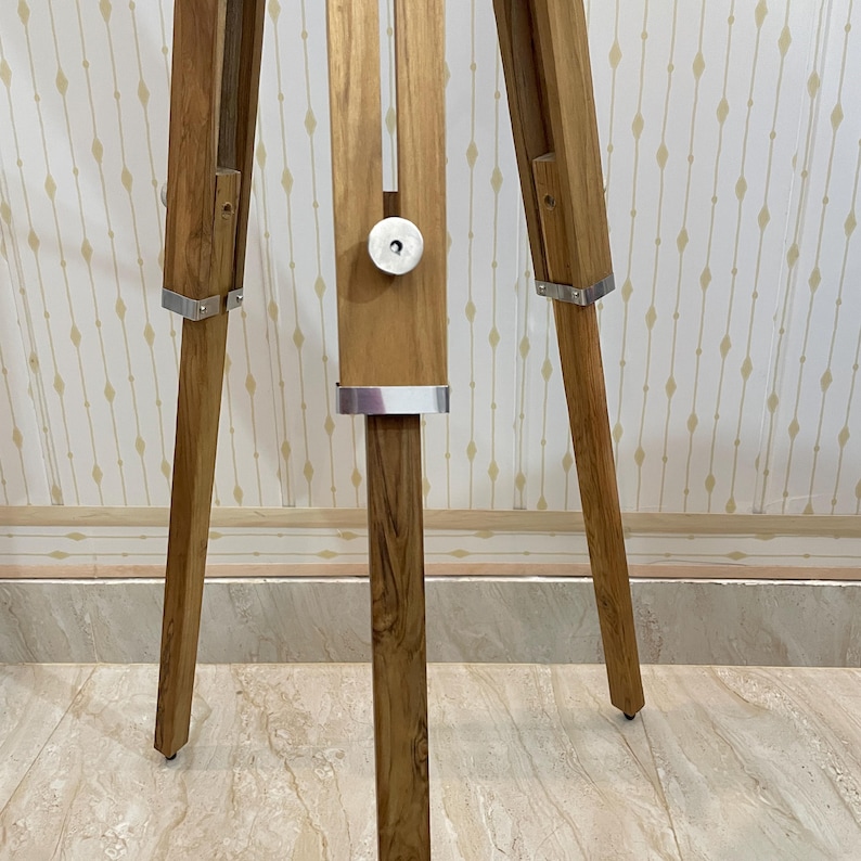 Vintage-style adjustable tripod stand handcrafted from premium teak wood with polished aluminium and nickel hardware. Features three sturdy wooden legs, an adjustable center column, and a height range of 25 to 50 inches. Ideal for DIY photo booths, DSLR cameras, floor lamps, studio décor, and nautical-inspired interiors. Handcrafted wooden tripod with a timeless industrial design.