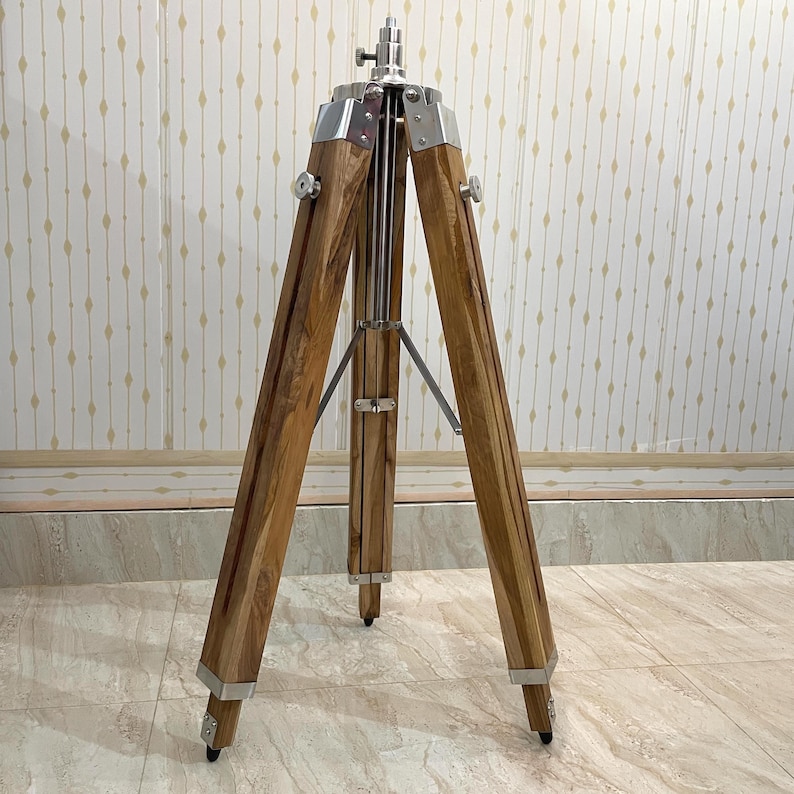 Vintage-style adjustable tripod stand handcrafted from premium teak wood with polished aluminium and nickel hardware. Features three sturdy wooden legs, an adjustable center column, and a height range of 25 to 50 inches. Ideal for DIY photo booths, DSLR cameras, floor lamps, studio décor, and nautical-inspired interiors. Handcrafted wooden tripod with a timeless industrial design.