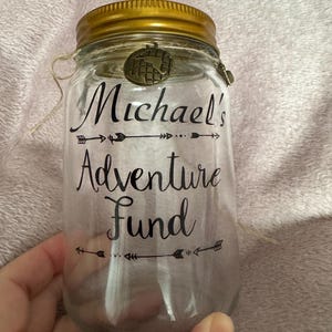 Piggy bank, savings jar with removable lid. Can be personalised to suit your requirements. The jar features 3 charms on string also.