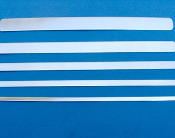 May include: Five silver metal strips of varying lengths, arranged vertically on a blue background.