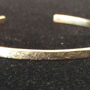 May include: A silver bracelet with a hammered texture.