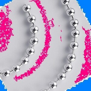 May include: A silver chain necklace with round links. The chain is arranged in a curved shape, creating a decorative design.