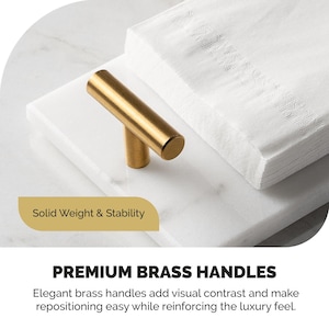 May include: A gold-colored brass handle with a cylindrical design, resting on a white marble surface. A stack of white napkins is in the background. The text "PREMIUM BRASS HANDLES" is visible.