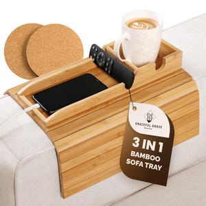 May include: A bamboo sofa tray with multiple compartments. It holds a white mug with a beverage, a remote control, and a smartphone. Two cork coasters are also included. The tray has the text "3 IN 1 BAMBOO SOFA TRAY".