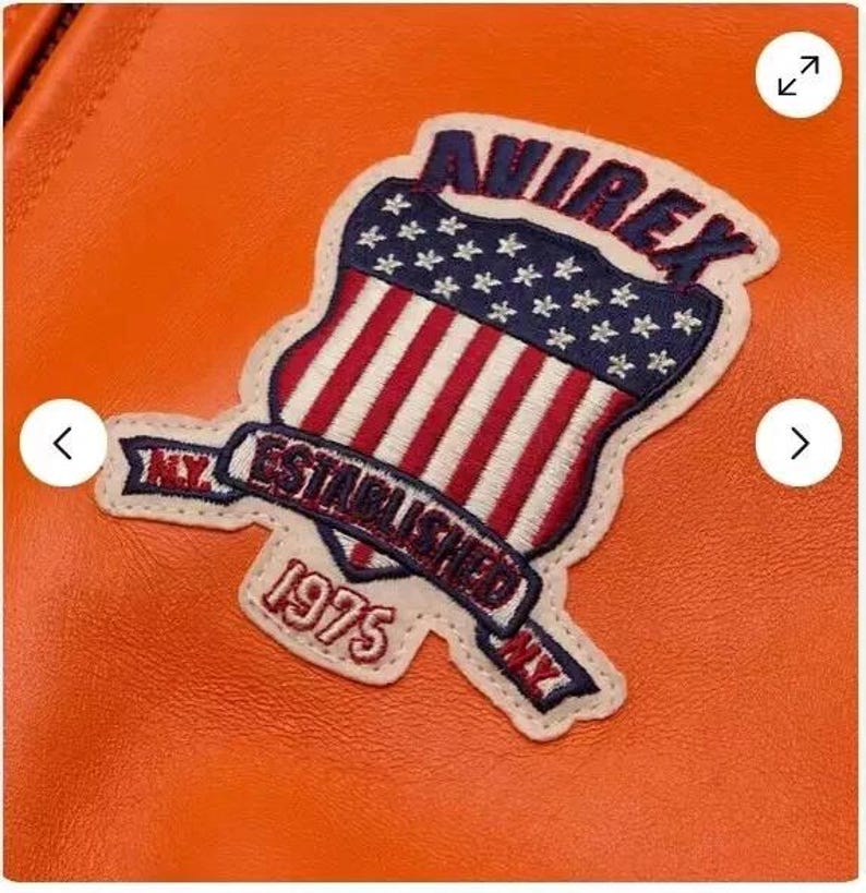 May include: Orange leather jacket with a patch featuring a shield with an American flag design and the text "Avirex Established 1975 NY."