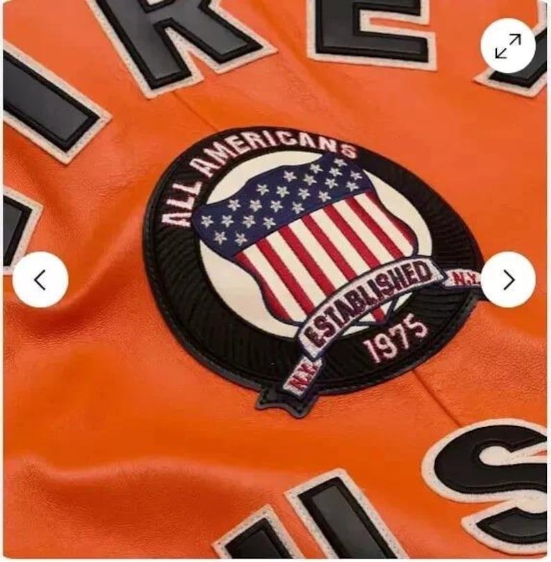 May include: Orange leather jacket with a black and white patch that says "All Americans NY Established 1975" and a black and white "US" patch.