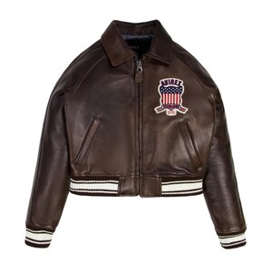 May include: A brown leather bomber jacket with a zip-up front, a collar, and a ribbed hem and cuffs with white stripes. The jacket features a patch on the chest with the text "AVIREX" and a patriotic design.