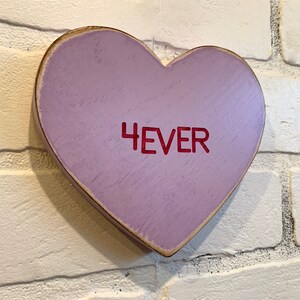 May include: A purple wooden heart-shaped sign with the word "4EVER" written in red.
