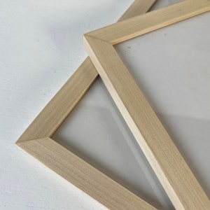 May include: Two natural wood picture frames, one on top of the other, with a white background.