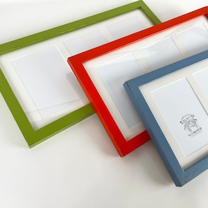 May include: Three rectangular picture frames with white matting, each featuring three openings. The frames are colored lime green, bright orange, and slate blue. The blue frame contains a label with the text SIGNED NUMBERED.