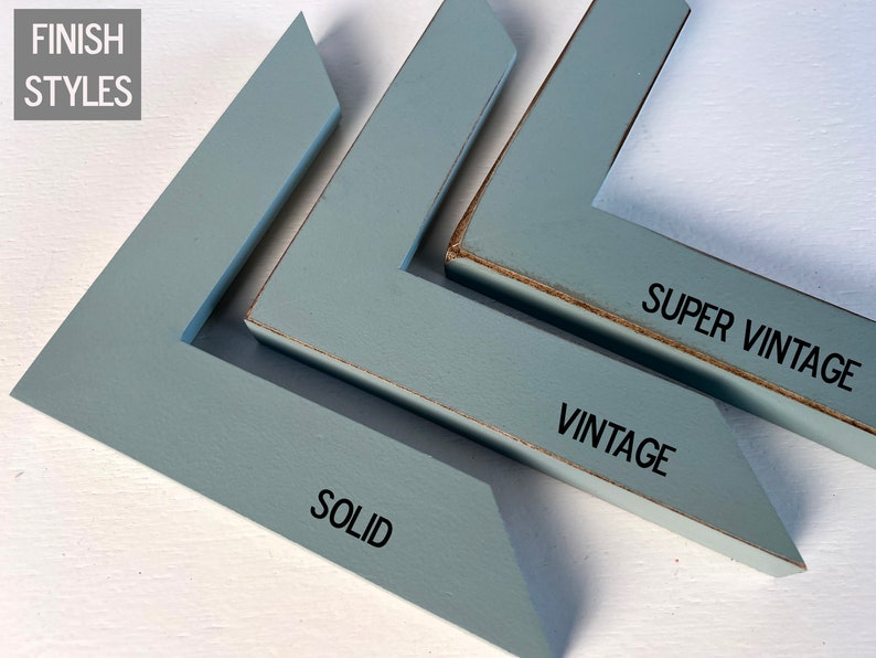 May include: Three L-shaped blue wooden frame corner samples labeled FINISH STYLES. The first is labeled SOLID with a smooth finish. The second is labeled VINTAGE with worn edges. The third is labeled SUPER VINTAGE with heavily distressed edges.