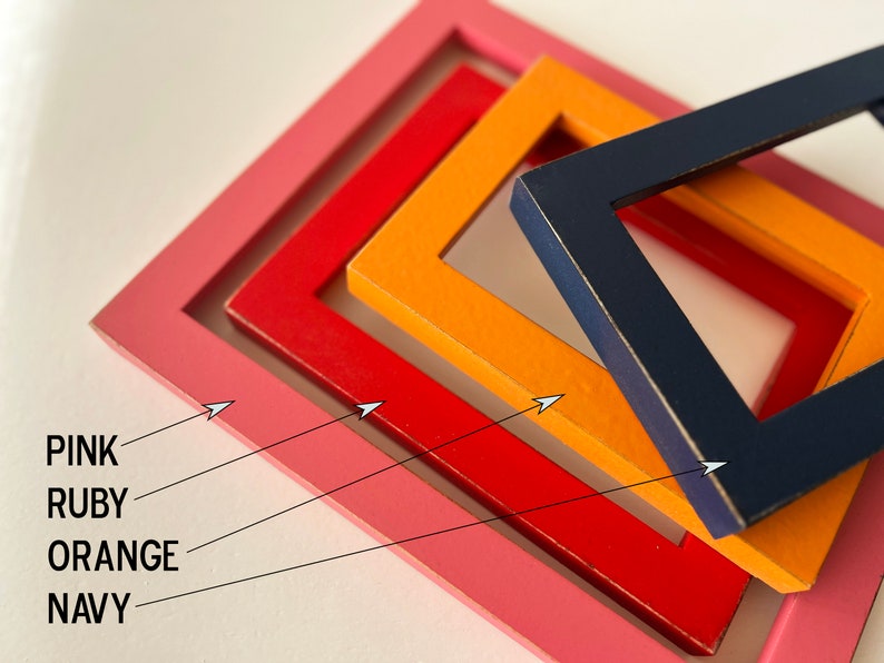 May include: Four square picture frames nested inside each other. The frames are painted in different colors: pink, ruby red, orange, and navy blue.