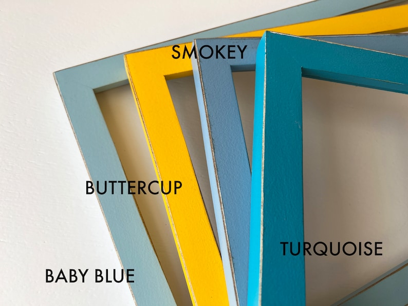 May include: Four wooden picture frames in different colors: baby blue, buttercup yellow, smokey blue, and turquoise. The frames are stacked on top of each other.
