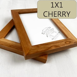 May include: Two 1x1 cherry wood picture frames stacked on top of each other. The frames are a light brown color and have a simple design.