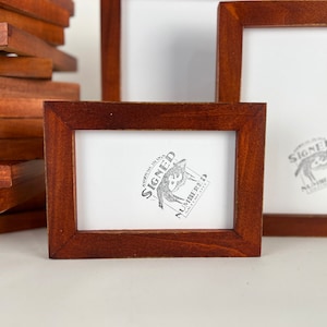 May include: Three wooden picture frames with a white background. The center frame has a black and white stamp that says "Signed & Numbered".