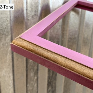 May include: A rectangular picture frame featuring a two-tone finish with a matte pink outer edge and a natural wood-toned inner trim. The frame has a beveled profile and includes the text 1x1 2-Tone in the upper left corner of the image.