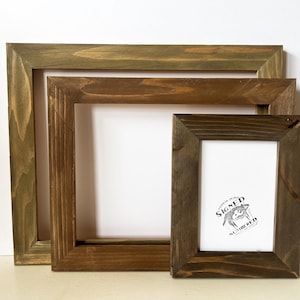 May include: Three wooden picture frames in different sizes, all with a dark brown stain. The smallest frame has a white background with the text "SIGNED" and a small graphic.