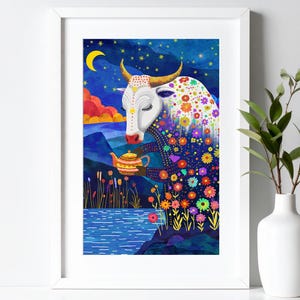 Puede incluir: Una impresión artística enmarcada que presenta una ilustración caprichosa de una vaca blanca sosteniendo una tetera. La vaca está adornada con patrones florales coloridos sobre un fondo de un cielo estrellado, montañas y un lago. La obra de arte está enmarcada en un borde blanco.