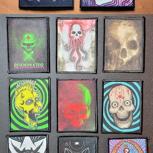 May include: Ten embroidered patches featuring various skull designs. The patches are black with white, red, green, and blue accents. Some patches feature text, including "Reanimator" and "30C".