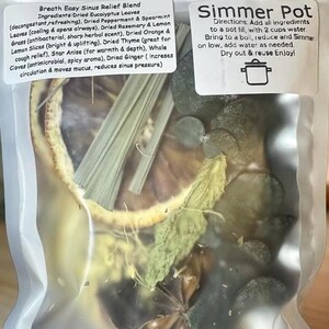 May include: A clear plastic bag containing dried herbs and spices for a simmer pot. The bag includes dried eucalyptus leaves, peppermint, rosemary, lemon grass, orange slices, thyme, star anise, cloves, and ginger. Text on the bag reads "Breath Easy Sinus Relief Blend" and "Simmer Pot".