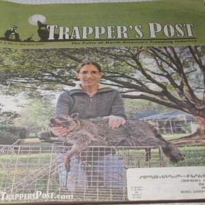 May include: A vintage copy of "Trapper's Post" magazine. The cover features a person holding a raccoon over a wire cage. The magazine's title is in large white letters on a green background, with the text "The Pulse of North America's Trapping Industry."