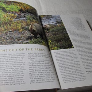 May include: A book open to a photograph of a bear in a natural environment. The text "THE GIFT OF THE PARKS" is displayed, accompanied by text discussing national parks and conservation.