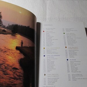 May include: Open book with a photograph of a person fishing in a river at sunset. The right page shows a detailed table of contents with various geographical regions.