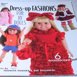 May include: A book cover titled "Dress-up Fashions for 18" Dolls" featuring crochet doll outfits. The cover shows dolls in various outfits, including a red dress, a pink coat, and blue shorts. The book includes 6 accessorized outfits.