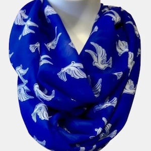 Op de afbeelding: Een koninklijk blauwe oneindige sjaal met een wit duivenpatroon. De sjaal is gemaakt van een zachte, lichtgewicht stof en is perfect om een ​​toets van elegantie aan elke outfit toe te voegen.