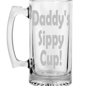Puede incluir: Una jarra de cerveza de vidrio transparente con asa. La jarra está grabada con el texto "Daddy's Sippy Cup!"