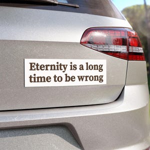 May include: A white bumper sticker on a silver car with the text "Eternity is a long time to be wrong".